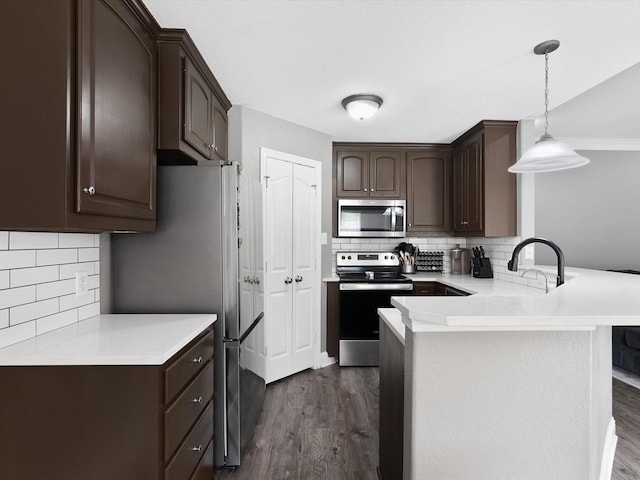 kitchen with decorative light fixtures, dark brown cabinets, kitchen peninsula, and stainless steel appliances