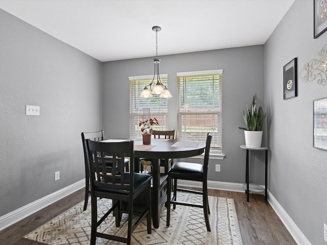 dining area with hardwood / wood-style floors and an inviting chandelier