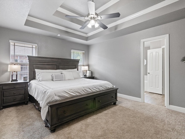 carpeted bedroom with ensuite bathroom, a raised ceiling, ceiling fan, and crown molding