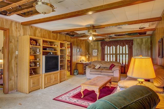 living room with carpet, ceiling fan, wood walls, and beamed ceiling