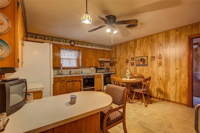 kitchen featuring ceiling fan, black dishwasher, hanging light fixtures, wooden walls, and range with electric stovetop