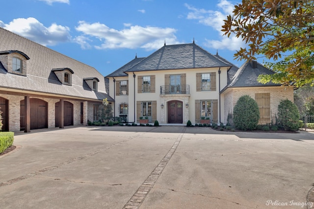 french country style house featuring a garage and a balcony