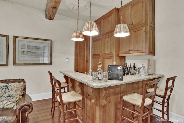 kitchen with kitchen peninsula, beam ceiling, light wood-type flooring, pendant lighting, and a breakfast bar area