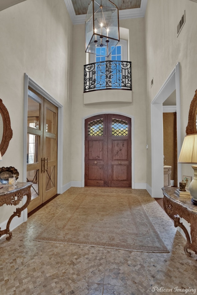 foyer with a high ceiling, crown molding, and a chandelier