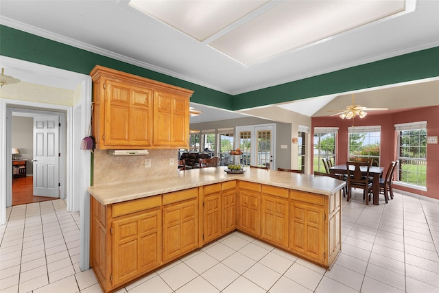 kitchen with backsplash, kitchen peninsula, ceiling fan, and light tile patterned flooring