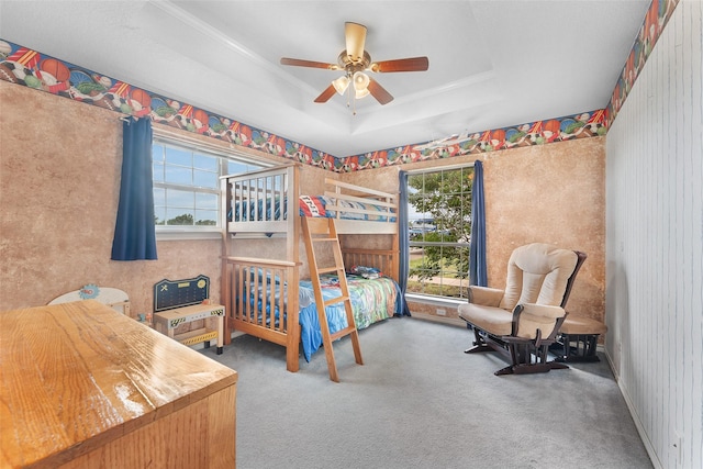 bedroom with a tray ceiling, ceiling fan, and carpet flooring