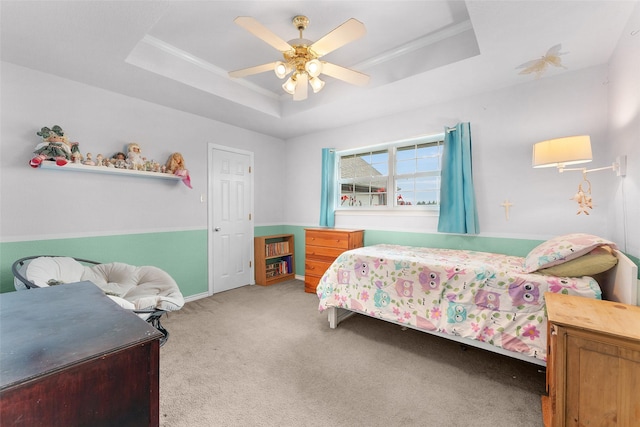 bedroom with a raised ceiling, ceiling fan, light colored carpet, and ornamental molding