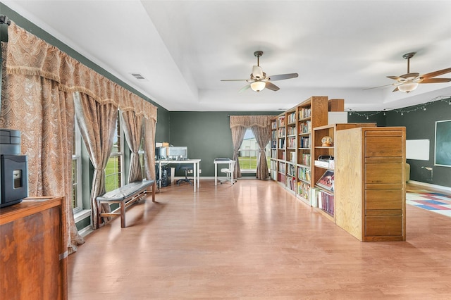 living area with light wood-type flooring and a raised ceiling