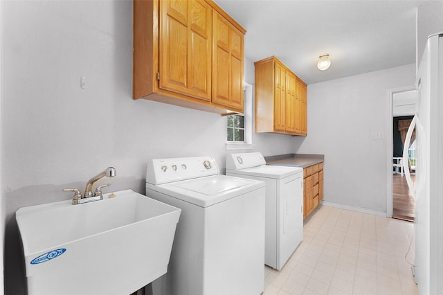 laundry area featuring washing machine and dryer, sink, and cabinets