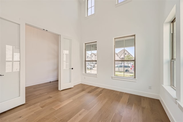 unfurnished bedroom with a high ceiling and light hardwood / wood-style floors