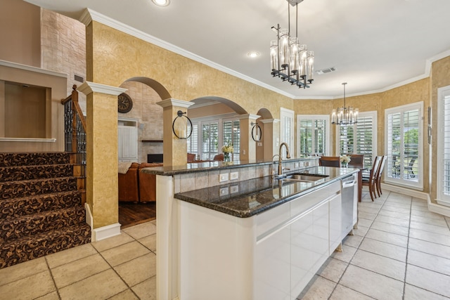 kitchen with pendant lighting, ornamental molding, a chandelier, and sink