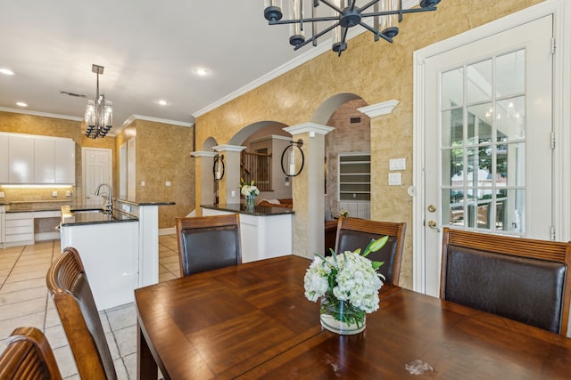 tiled dining space featuring ornate columns, ornamental molding, sink, and a notable chandelier