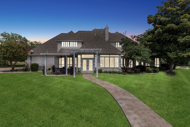 back house at dusk with a pergola, a yard, and a patio