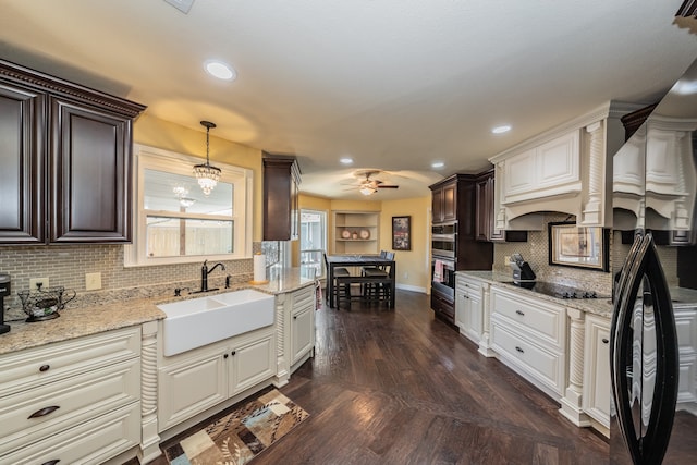 kitchen featuring light stone countertops, dark wood-type flooring, hanging light fixtures, backsplash, and sink