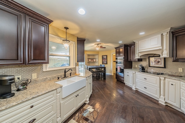 kitchen with tasteful backsplash, decorative light fixtures, sink, stainless steel double oven, and white cabinetry