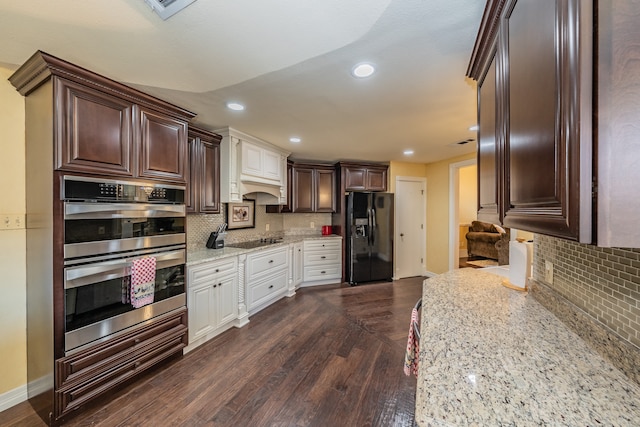 kitchen with dark brown cabinets, tasteful backsplash, black appliances, dark hardwood / wood-style flooring, and light stone counters