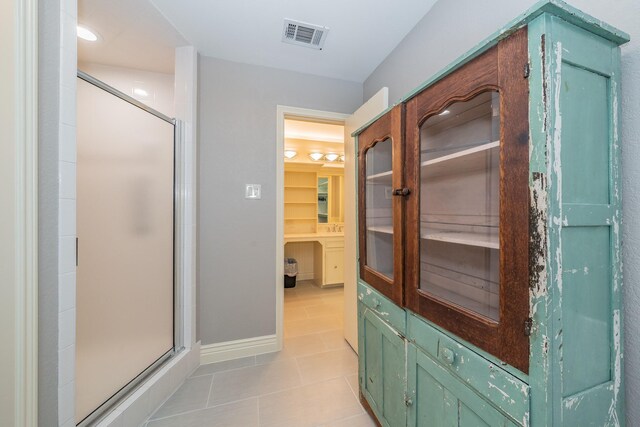 bathroom featuring a shower with door and tile flooring