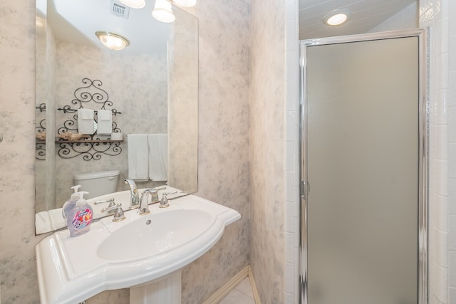 bathroom featuring sink, toilet, and a shower with door