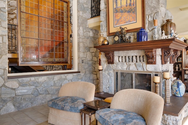 sitting room with tile patterned floors and a stone fireplace