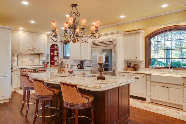 kitchen with sink, dark hardwood / wood-style floors, decorative backsplash, an island with sink, and decorative light fixtures