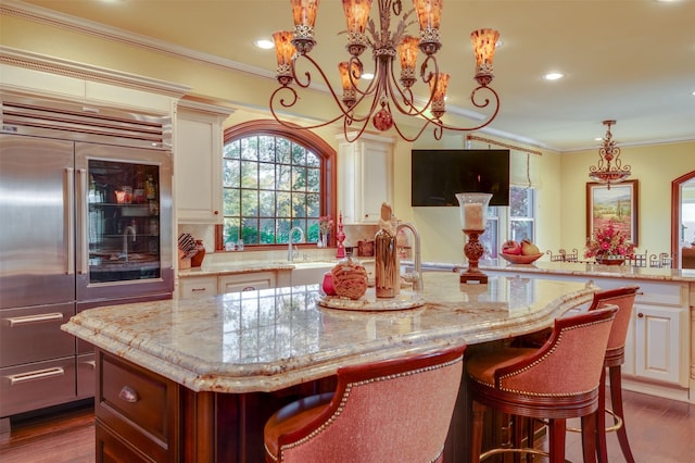 kitchen with light stone countertops, built in refrigerator, a kitchen island, and hanging light fixtures