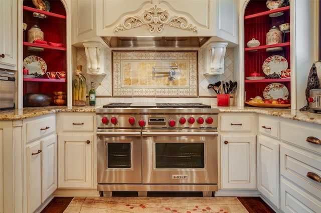 kitchen with designer range, light stone counters, and tasteful backsplash