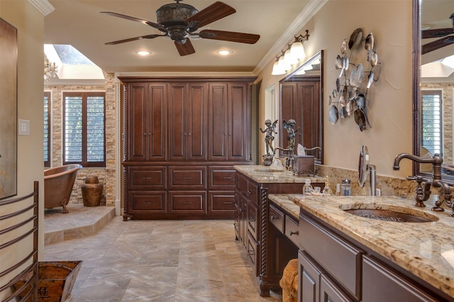 bathroom featuring vanity, a bath, a skylight, ceiling fan, and ornamental molding