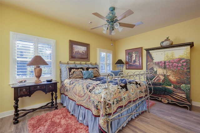 bedroom with multiple windows, hardwood / wood-style flooring, and ceiling fan