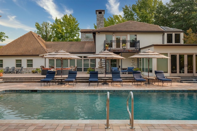 back of property featuring a balcony, a patio, and french doors