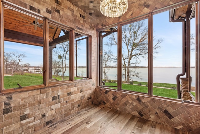 unfurnished sunroom with an inviting chandelier, hardwood / wood-style flooring, and a water view