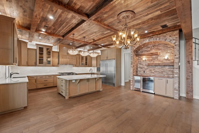 kitchen with built in refrigerator, a center island, sink, hanging light fixtures, and beam ceiling