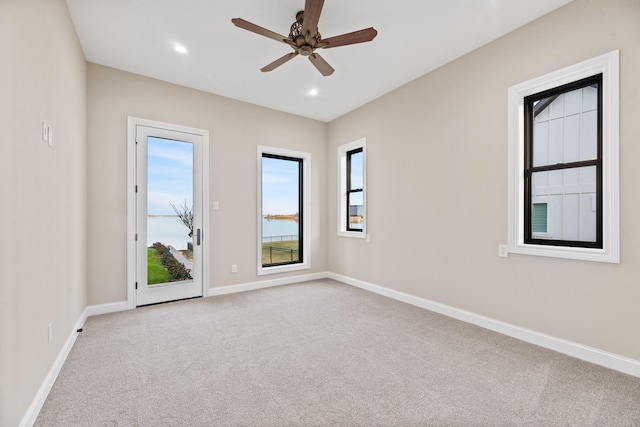 unfurnished room with light colored carpet and ceiling fan