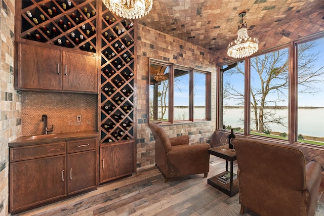 wine cellar featuring a chandelier, brick ceiling, hardwood / wood-style flooring, and a sink