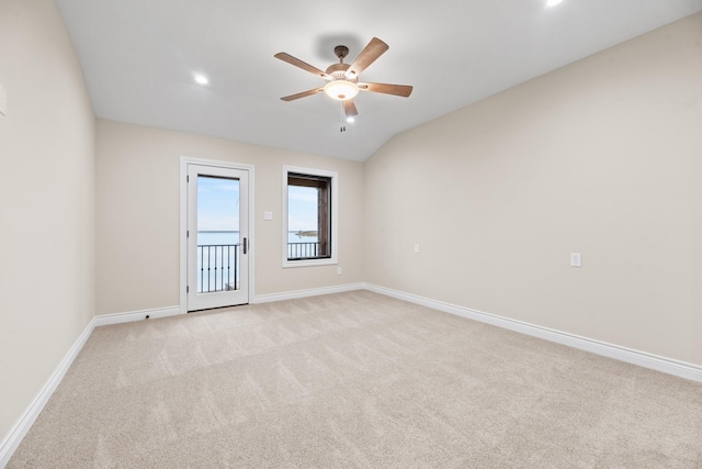 carpeted spare room with ceiling fan and vaulted ceiling