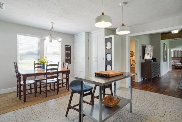 dining space with a notable chandelier, a textured ceiling, and hardwood / wood-style flooring