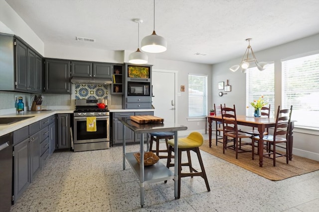 kitchen with decorative light fixtures, a healthy amount of sunlight, backsplash, and appliances with stainless steel finishes