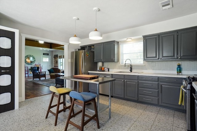 kitchen featuring hanging light fixtures, tasteful backsplash, sink, light tile floors, and appliances with stainless steel finishes