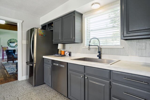 kitchen with a textured ceiling, gray cabinetry, stainless steel appliances, sink, and light tile flooring