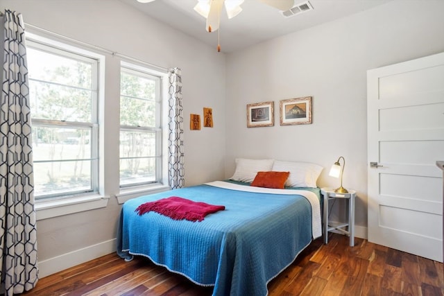 bedroom with dark hardwood / wood-style floors, ceiling fan, and multiple windows