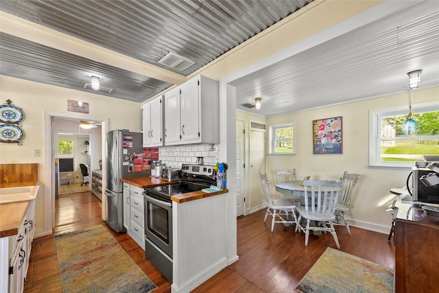 kitchen featuring tasteful backsplash, butcher block counters, hanging light fixtures, white cabinetry, and appliances with stainless steel finishes