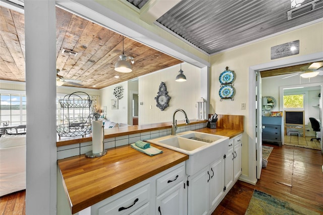 kitchen with pendant lighting, visible vents, wood ceiling, white cabinets, and a sink