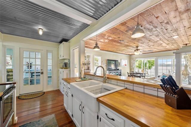 kitchen featuring hanging light fixtures, dark wood-type flooring, white cabinetry, a sink, and wooden ceiling