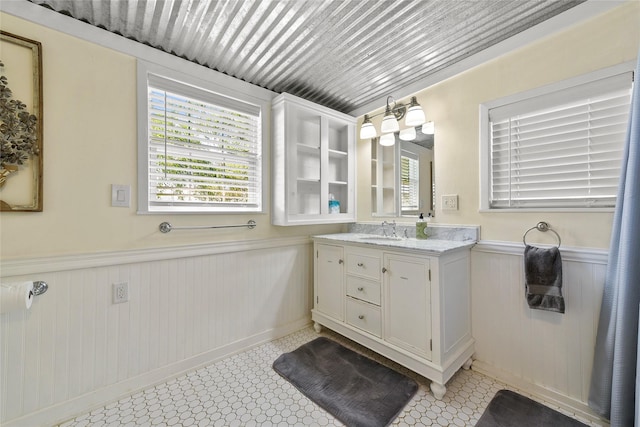 bathroom with a wainscoted wall, plenty of natural light, wooden ceiling, and vanity