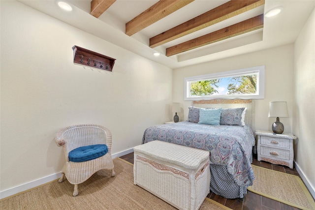 bedroom featuring baseboards, beam ceiling, and wood finished floors