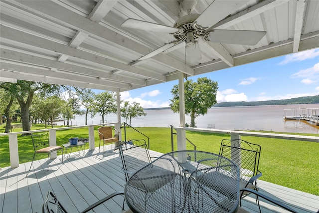 wooden deck with ceiling fan, a water view, and a yard