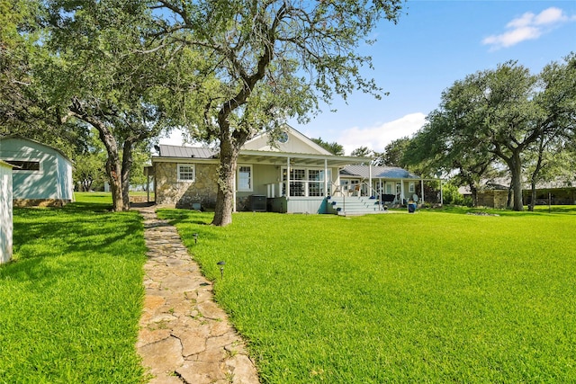 rear view of property with metal roof, a porch, stone siding, a lawn, and a standing seam roof