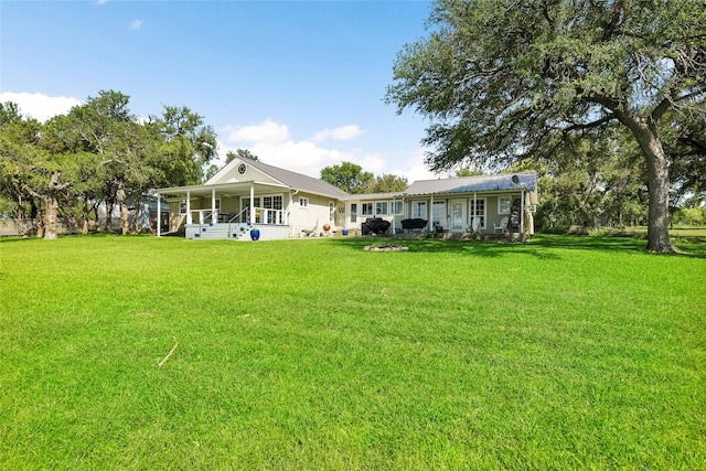 rear view of property featuring covered porch and a lawn