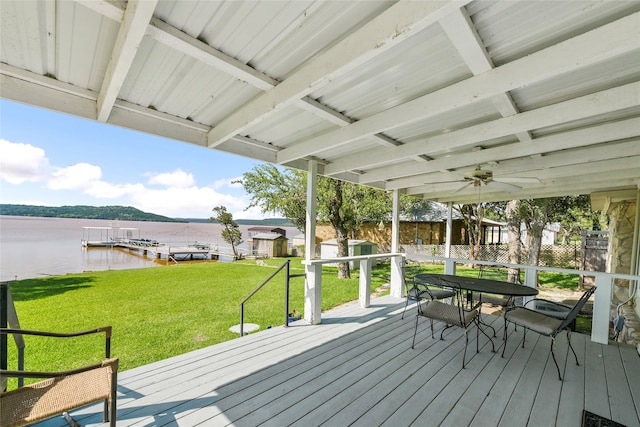 wooden deck featuring a yard, ceiling fan, a water view, and a dock