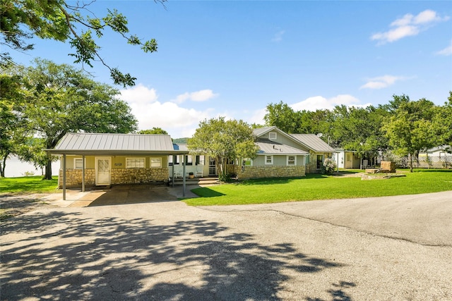 view of front of house featuring driveway, stone siding, a front lawn, and metal roof