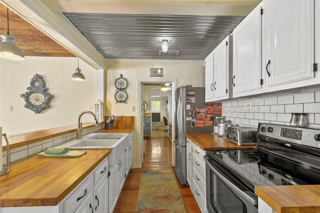 kitchen featuring appliances with stainless steel finishes, white cabinets, butcher block countertops, and hanging light fixtures